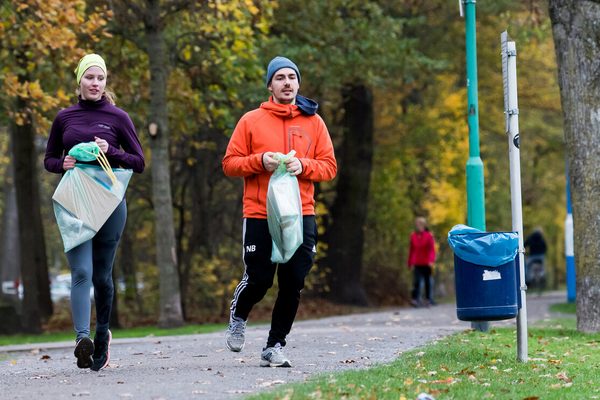 2 Sportler*innen sammeln Müll ein während des Laufens durch den Park